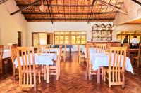 a dining room with white tables and wooden chairs at Andasibe Sifaka Lodge in Andasibe