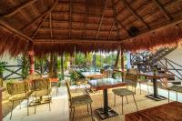 een restaurant met tafels en stoelen en een rieten dak bij Azulea Bacalar Hotel & Spa - Lagoon Front in Bacalar