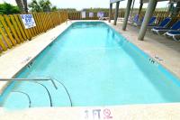 einen großen blauen Pool mit Stühlen und einem Zaun in der Unterkunft Windy Waves Top Location w Pool in Myrtle Beach