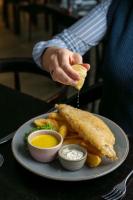 una persona che tiene un pezzo di cibo su un piatto di St Moritz Hotel Apartments a Polzeath