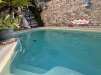 einen Pool mit blauem Wasser vor einer Ziegelwand in der Unterkunft Les Grimaldines - Maison d&#39;Hôtes in Cagnes-sur-Mer