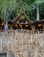 een bamboehek met een gebouw met een boom bij Wonderland Beach Resort in El Nido