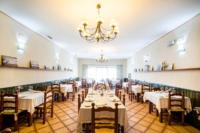 een eetkamer met tafels en stoelen en een kroonluchter bij La Hostería de Oropesa in Oropesa