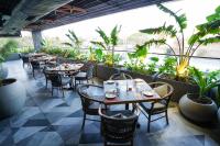 ein Restaurant mit Tischen, Stühlen und Pflanzen in der Unterkunft Hotel Tulips Grand in Hyderabad