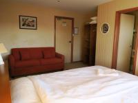 a bedroom with a bed and a red couch at Sundeck Hotel in Perisher Valley
