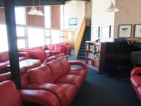 a waiting room with red leather couches and a piano at Sundeck Hotel in Perisher Valley