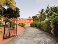 a driveway leading to a orange house with a gate at Anne Marie Villas in Castries
