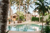 una piscina en un complejo con palmeras en Hotel Boutique Can Cocal El Cuyo, en El Cuyo