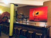a man playing guitar at a bar with a painting on the wall at Hidden Negombo By Sana's in Negombo