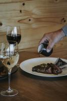 una persona che tiene un cucchiaio sopra un piatto di carne e vino di Iron Creek Bay Estate a Sorell