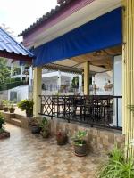 a patio with tables and chairs and a blue awning at Sawasdee Home Stay Resort & Pool in Khao Lak