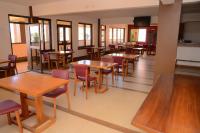 a restaurant with wooden tables and chairs and windows at Hotel Acacia View in Kampala
