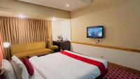 a hotel room with a bed and a tv on the wall at West Park Inn in Dhaka
