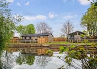 un par de casas sentadas junto a un cuerpo de agua en Lee Valley, en Hoddesdon
