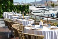 Una fila de mesas y sillas con barcos al fondo. en Hotel Port Salins by Pierre & Vacances, en Empuriabrava