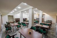 ein Restaurant mit Holztischen und grünen Stühlen in der Unterkunft Florence Hotel in Jizzax