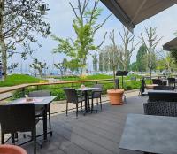 um pátio exterior com mesas, cadeiras e árvores em Hotel Mediterra em Uhldingen-Mühlhofen