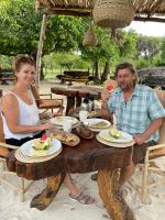 a man and woman sitting at a wooden table with food at Kwa Simba Tanzania in Pangani