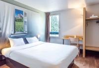 シャンベリにあるB&amp;B HOTEL CHAMBERY La Cassineの大きなベッドと机があるホテルの部屋