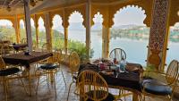 um restaurante com mesas e cadeiras e vista para a água em Young Monk Hostel Udaipur - Jaydurg Haveli em Udaipur