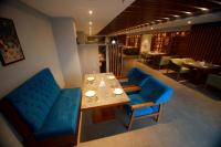 ein Esszimmer mit einem Tisch und blauen Stühlen in der Unterkunft Ambal Regency in Pudukād