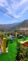 un balcón con césped verde con mesas y sillas en Sangam View Home stay, en Devaprayāg