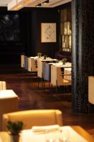 Un comedor con mesas y sillas blancas. en Le Metropolitan, Paris Tour Eiffel, a Tribute Portfolio Hotel, en París