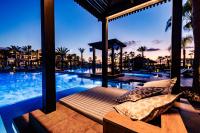 a bed with pillows next to a swimming pool at Hotel Riu Palace Tikida Agadir - All Inclusive in Agadir