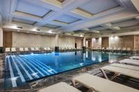 a pool in a hotel room with chairs and a table at Hotel Riu Palace Tikida Agadir - All Inclusive in Agadir