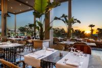 a restaurant with tables and chairs with the sunset in the background at Hotel Riu Palace Tikida Agadir - All Inclusive in Agadir