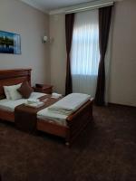 Un dormitorio con dos camas y una ventana con cortinas. en Maximum Hotel, en Navoi