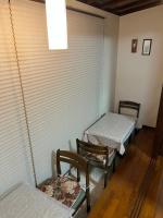 a room with two beds and two chairs and a window at Petit Hotel Hikobee in Kaga