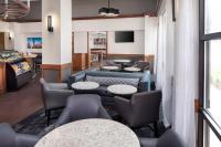 a waiting room with tables and chairs and a tv at Hyatt Place Atlanta Airport North in Atlanta