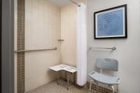 a bathroom with a shower and a chair and a stool at Hyatt Place Atlanta Airport North in Atlanta