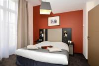 a bedroom with a bed with an orange wall at Odalys City Montpellier Les Occitanes in Montpellier