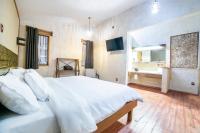Un dormitorio con una gran cama blanca y un baño. en Capital O Collection O Casona De Minas Mineral del Monte, en Mineral del Monte