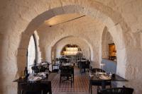 a restaurant with tables and chairs in a stone wall at Trulli Damari in Locorotondo