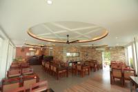a restaurant with wooden tables and chairs and a ceiling at Kappil Meadows in Varkala
