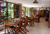 Au Bois Vert - Hôtel Ivato Airport في Abohijanahary: مطعم به طاولات وكراسي ونوافذ خشبية