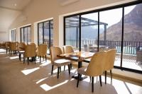 Un comedor con mesa y sillas y ventanas. en Lodges By Baron Hunza Attabad Lake, en Hunza