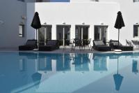 Una piscina con sillas y sombrillas al lado de un edificio. en Kallos Imar Boutique Hotel, en Mesariá