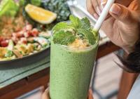 a person holding a green smoothie with a white straw at Stay Wellbeing & Lifestyle Resort in Rawai Beach