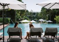 two women sitting in chairs next to a pool at Stay Wellbeing & Lifestyle Resort in Rawai Beach