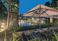 a table and chairs under an umbrella next to a pool at Stay Wellbeing & Lifestyle Resort in Rawai Beach