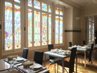 a dining room with two tables and stained glass windows at Hôtel De Normandie in Amiens