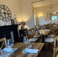 ein Restaurant mit Holztischen und einer großen Uhr an der Wand in der Unterkunft Morven Guest House Carnoustie in Carnoustie