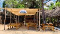 un restaurante con mesas de madera y sillas en la playa en Breezy Beach Cabanas, en Arugam Bay