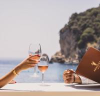 duas pessoas sentadas numa mesa com copos de vinho em Aragosta Suites em Paleokastritsa