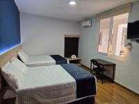 Una habitación de hotel con dos camas y una ventana. en Casa Sismarro Hotel, en Retalhuleu