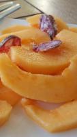 a plate of sliced papaya with a piece of fruit at Les Terrasses - Gordes in Gordes